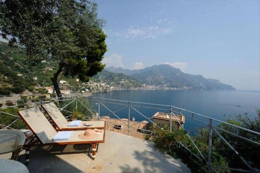 uma varanda com vista para um corpo de água em Villa Oliver - Breathtaking small Pool 14 sqm Hydromassage on the Rock - Amalfi Coast em Amalfi
