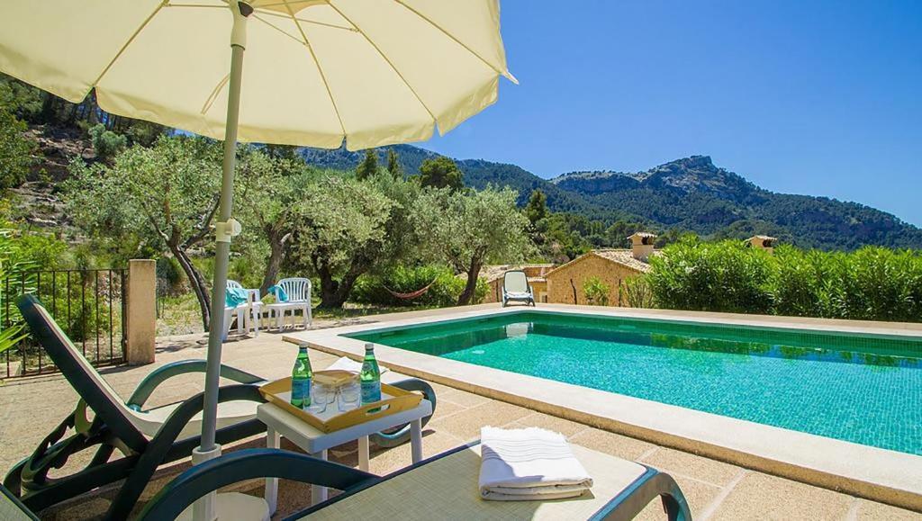een zwembad met een tafel en een parasol naast een tafel sidx sidx bij Villa Son Llarg, Estallencs in Estellencs