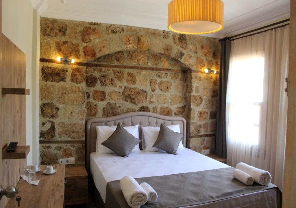a bedroom with a large bed with a stone wall at VILLA CASTLE INN in Antalya