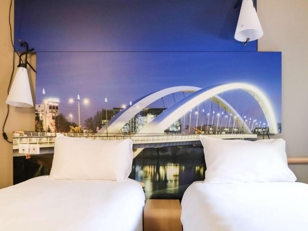 two beds in a room with a bridge in the background at ibis Lyon Gerland Merieux in Lyon