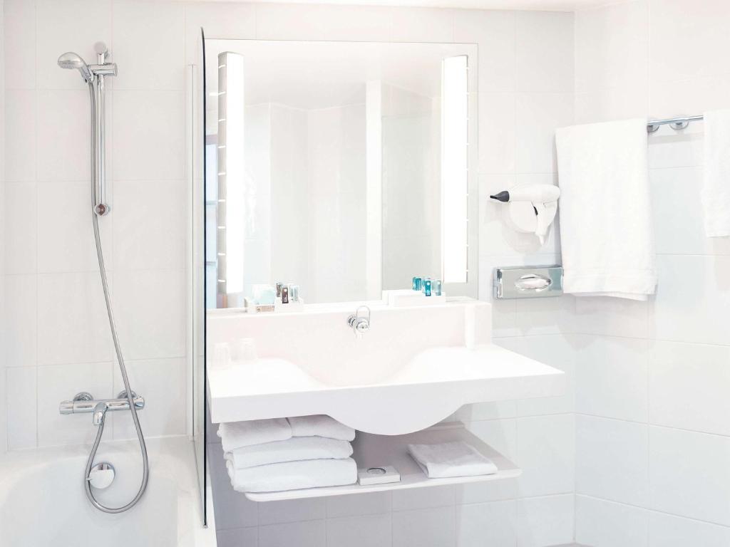 a white bathroom with a sink and a shower at Novotel Porto Gaia in Vila Nova de Gaia