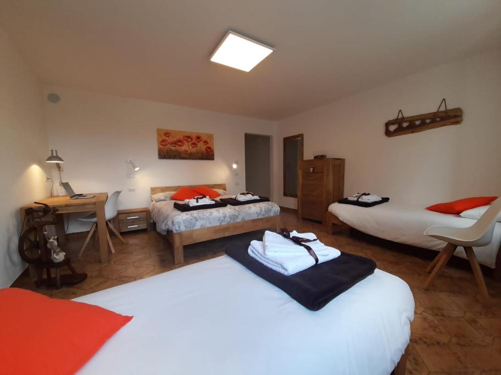a bedroom with two beds and a desk with a chair at B&B La casa di Loretta in Paderno