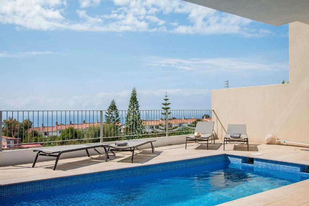 een zwembad met 2 stoelen en een tafel op een patio bij Capistrano Garden, piscina privada y vistas al mar in Nerja