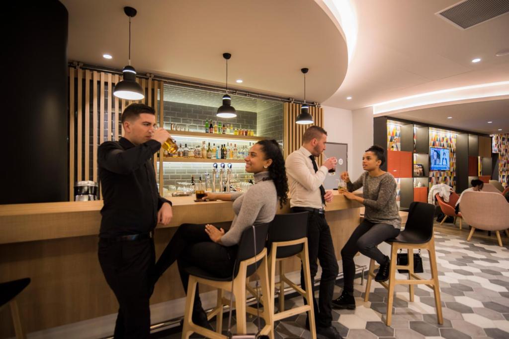 a group of people standing at a bar at Holiday Inn Express - Paris - CDG Airport by IHG in Roissy-en-France