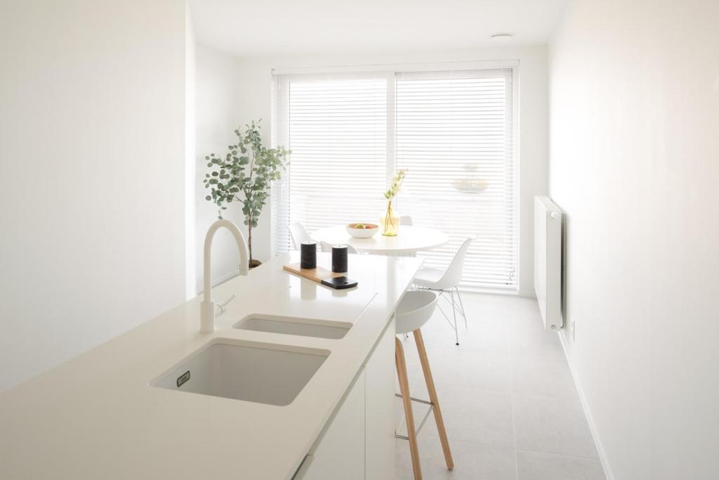 a white kitchen with a sink and a window at Zilverzand aan zee - frontaal zeezicht in Koksijde