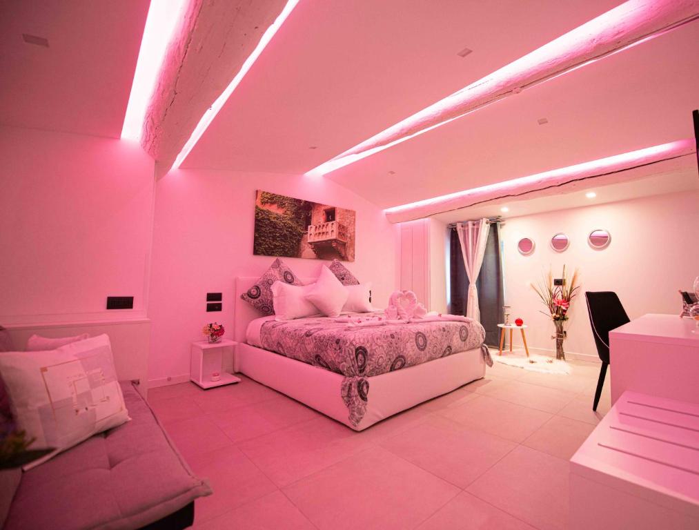 HOME CARPEDIEM في فيرونا: غرفة نوم وردية مع سرير وأريكة