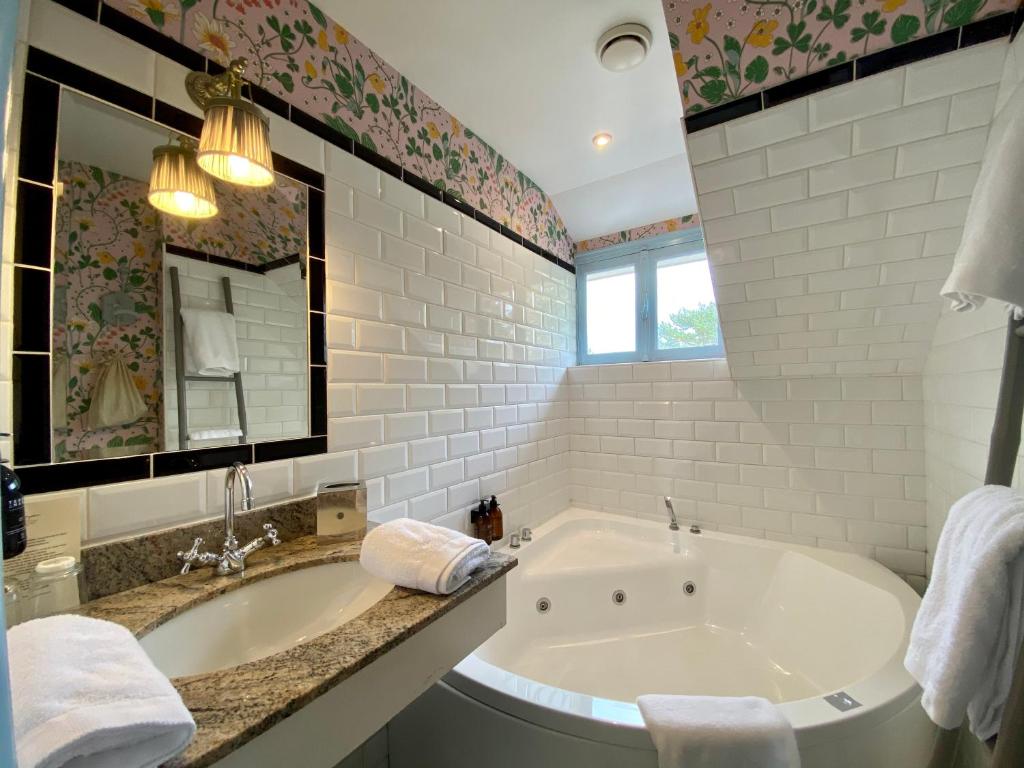 a white bathroom with a tub and a sink at Domaine Saint Clair - Le Donjon in Étretat