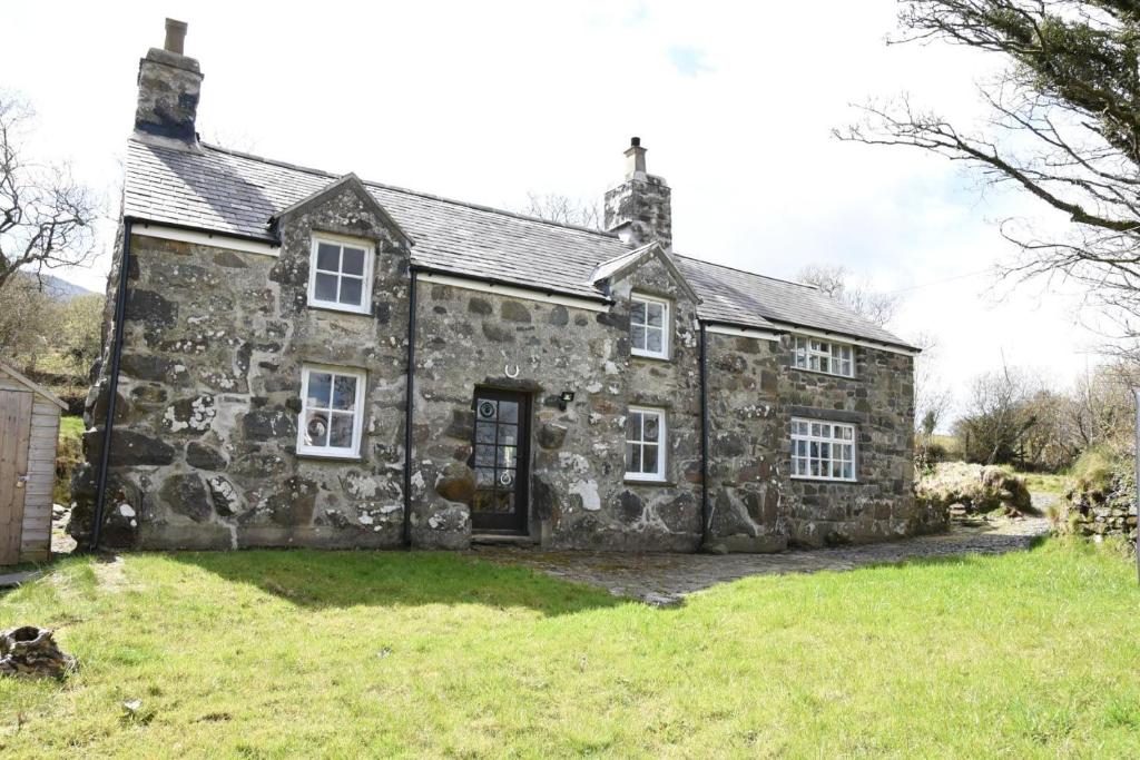 an old stone house on a grassy field at Ty-Gwyn Cottage in Clynnog-fawr