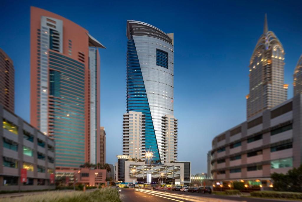 Staybridge Suites Dubai Internet City, an IHG Hotel في دبي: مبنى طويل في مدينة ذات مباني طويلة