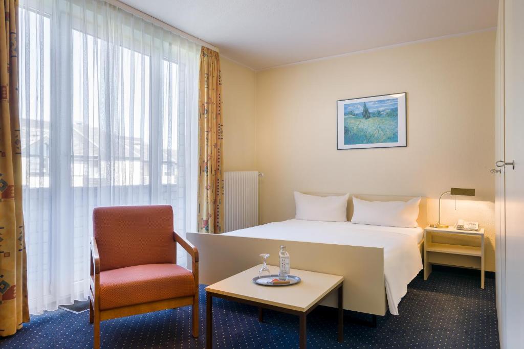 a hotel room with a bed and a chair at acora Bonn Living the City - Apartments in Bonn