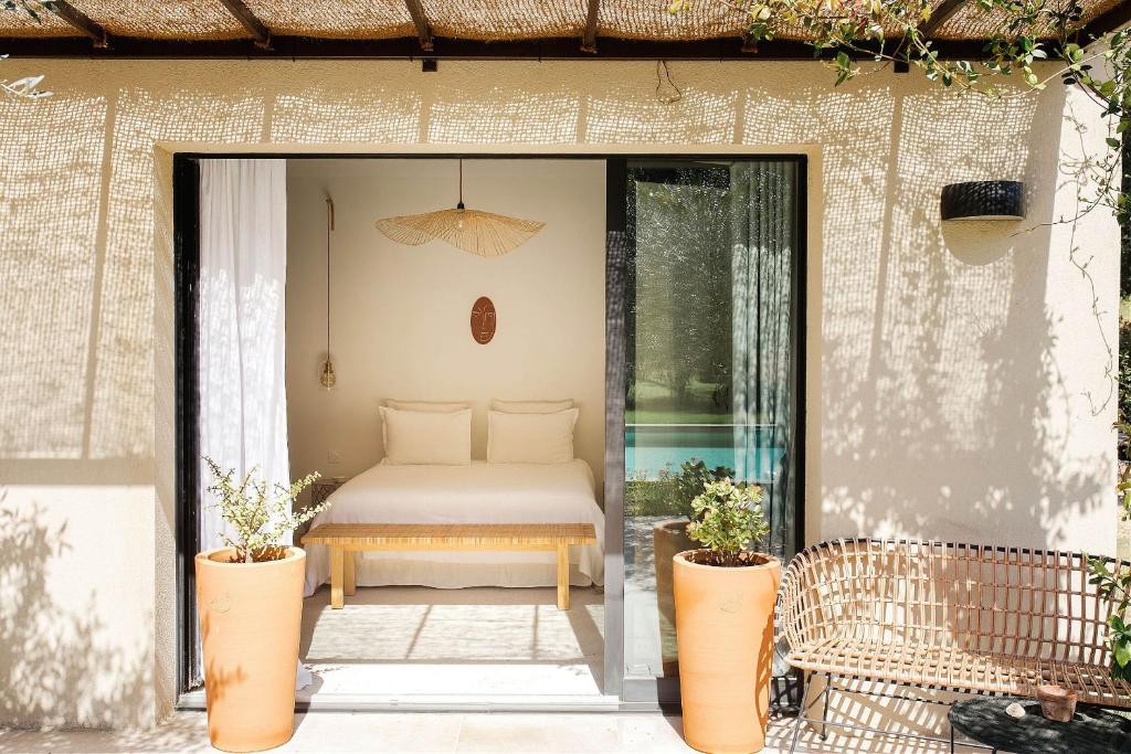 une terrasse avec un lit et deux plantes en pot dans l'établissement La Roussatino, à Saint-Étienne-du-Grès