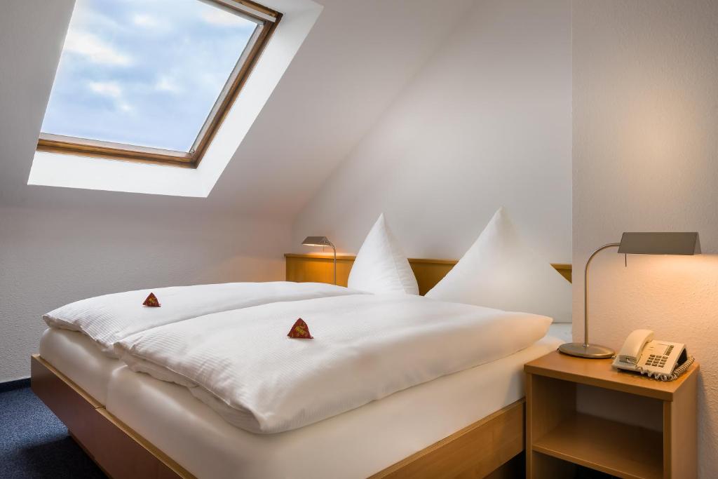 Schlafzimmer mit einem weißen Bett und einem Fenster in der Unterkunft acora Karlsruhe Zentrum Living the City - Apartments in Karlsruhe