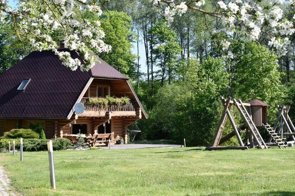 uma cabana de madeira com um parque infantil no quintal em Kastaņas em Kaibala