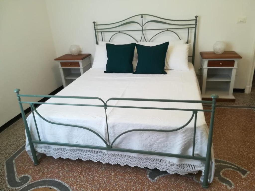 una camera da letto con un grande letto bianco con cuscini verdi di La casa di Via Defferrari a Noli