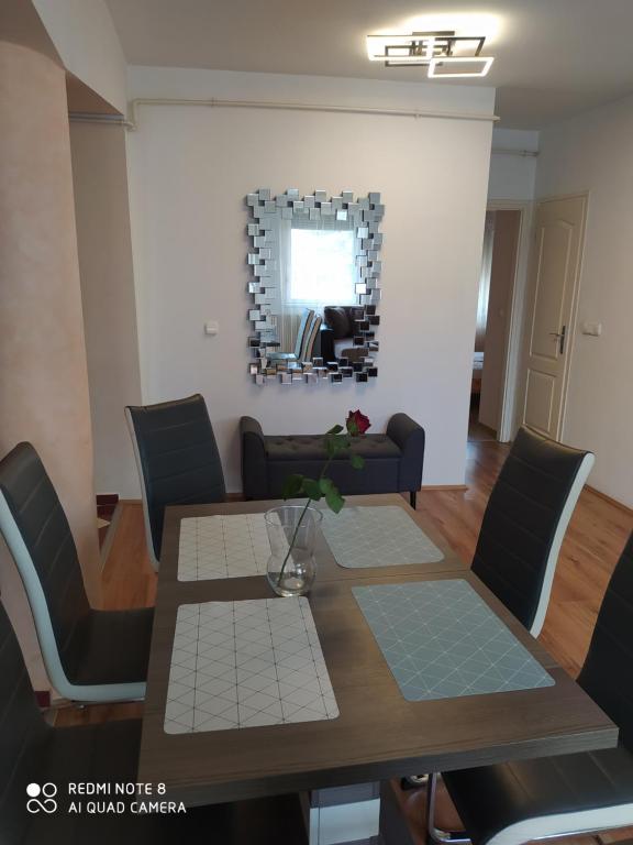 a dining room with a table and chairs and a mirror at Kristály Apartman in Szeged