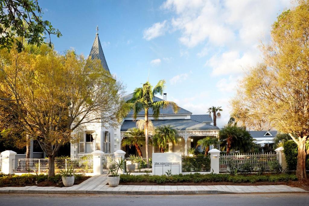 ein weißes Haus mit einem Turm und Bäumen in der Unterkunft The Robertson Small Hotel and Spa by The Living Journey Collection in Robertson