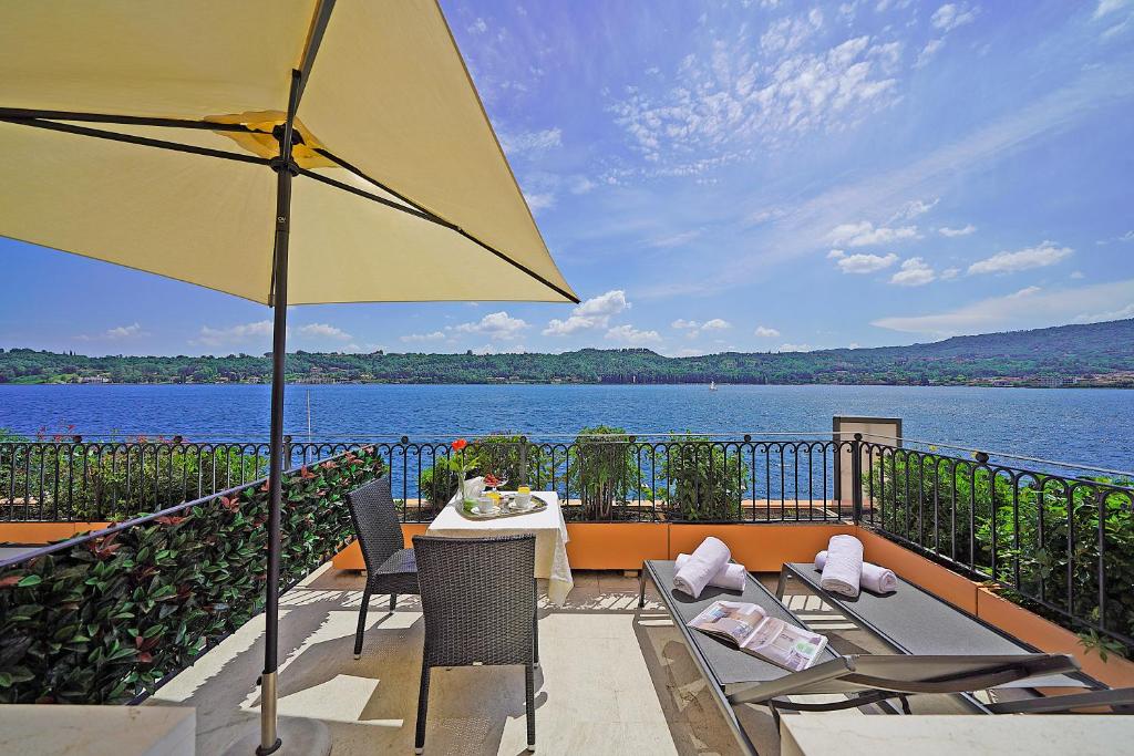 une terrasse avec une table, des chaises et un parasol dans l'établissement Hotel Vigna, à Salò