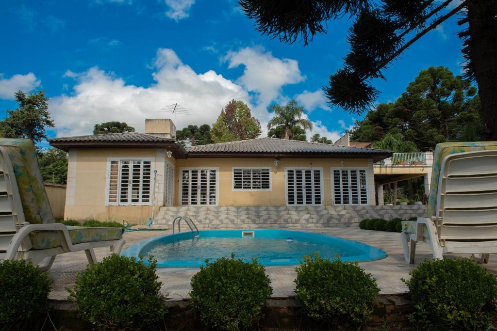 ein Haus mit einem Pool und zwei Gartenstühlen in der Unterkunft Casa com WiFi e lazer em Campina Grande do Sul in Campina Grande do Sul