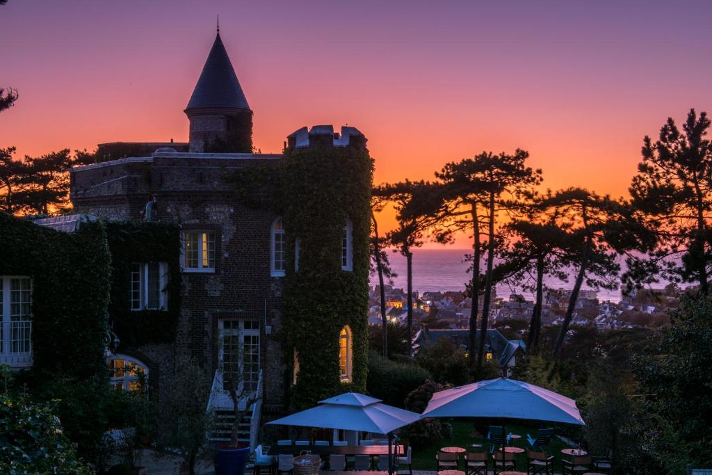 a building with a tower with a sunset in the background at Domaine Saint Clair - Le Donjon in Étretat