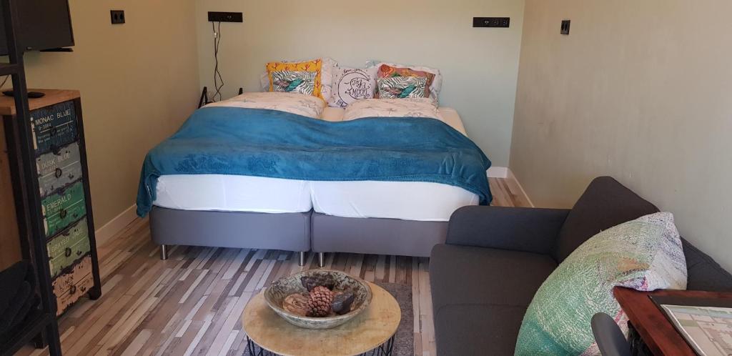 um pequeno quarto com uma cama e um sofá em JaBaKi Green Studio em Hoofddorp