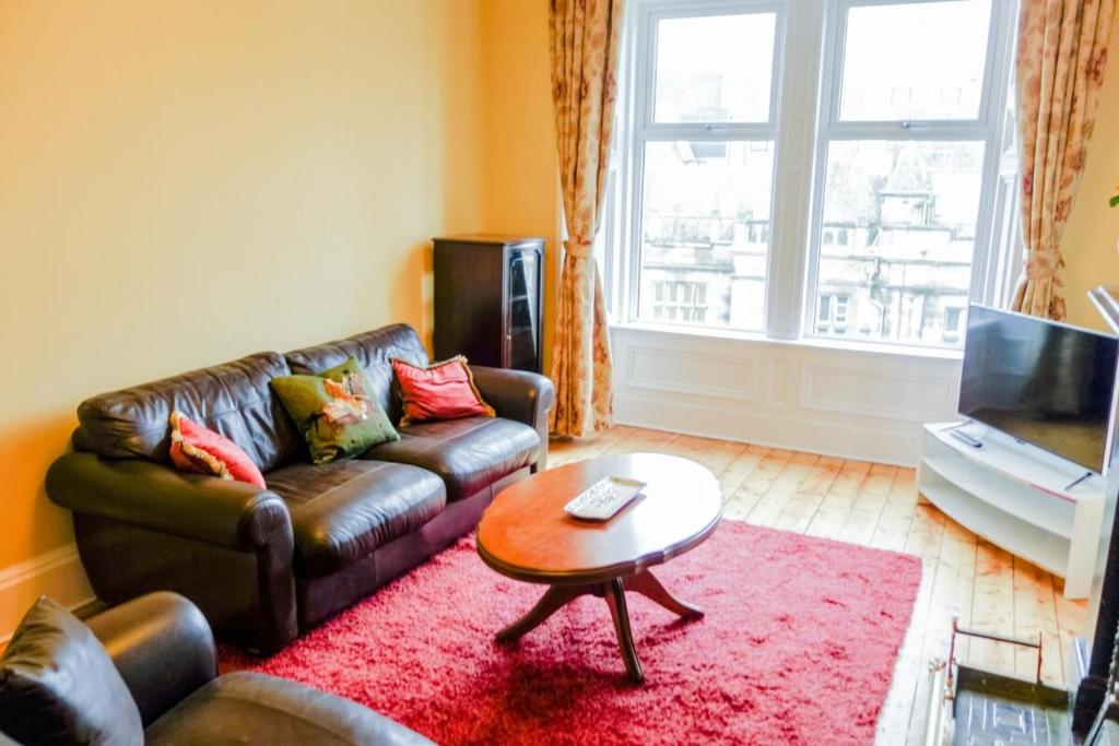 エディンバラにあるNewly Furnished 2 Bedroom Apartment on Leith Walkのリビングルーム(革張りのソファ、テーブル付)