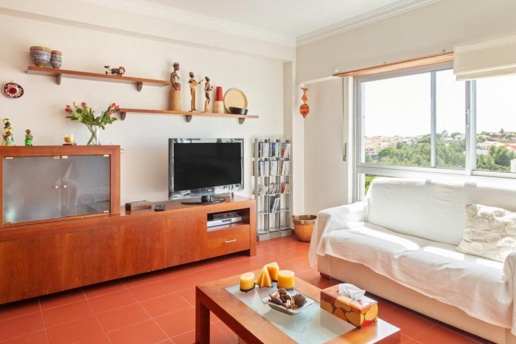 ein Wohnzimmer mit einem weißen Sofa und einem TV in der Unterkunft Lovely 2 Bedroom Apartment with Terrace in Cascais in Lissabon