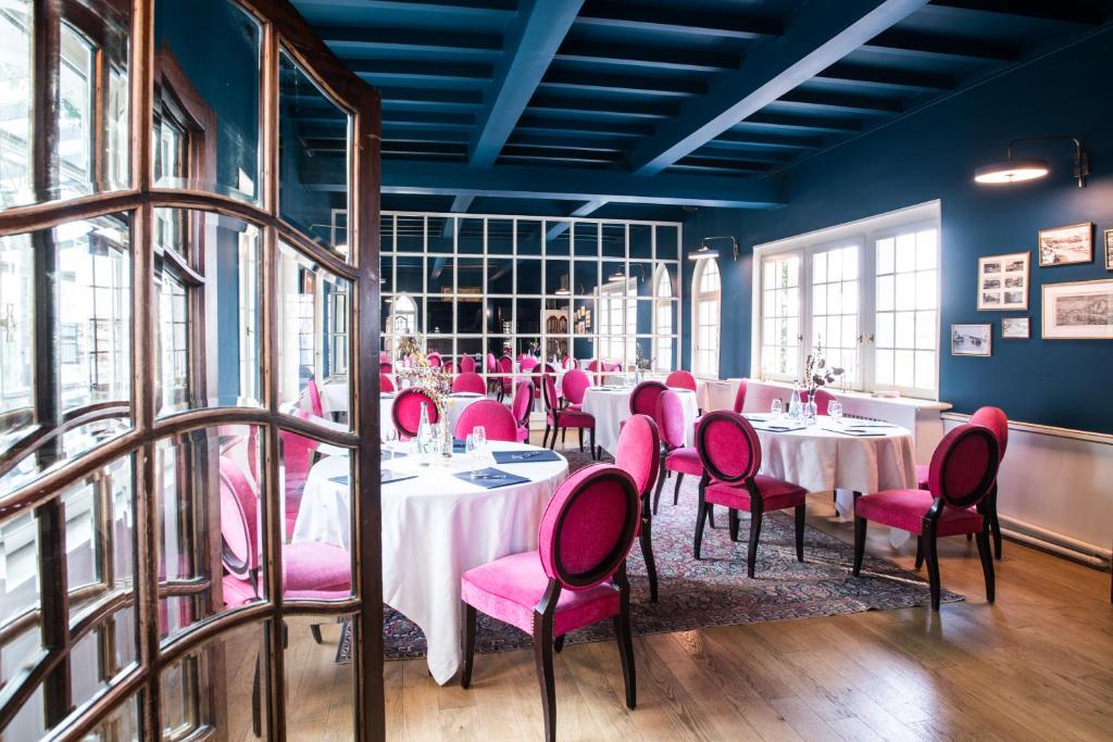 a dining room with tables and pink chairs at Domaine Saint Clair - Le Donjon in Étretat