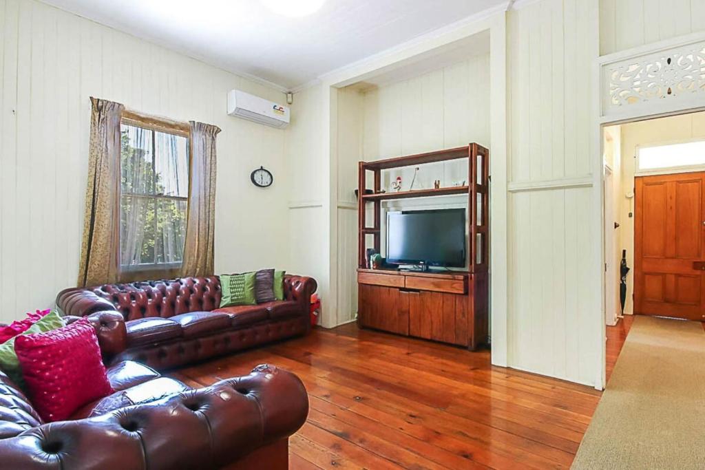 a living room with leather couches and a television at Walk to the Charming Character Home in Brisbane