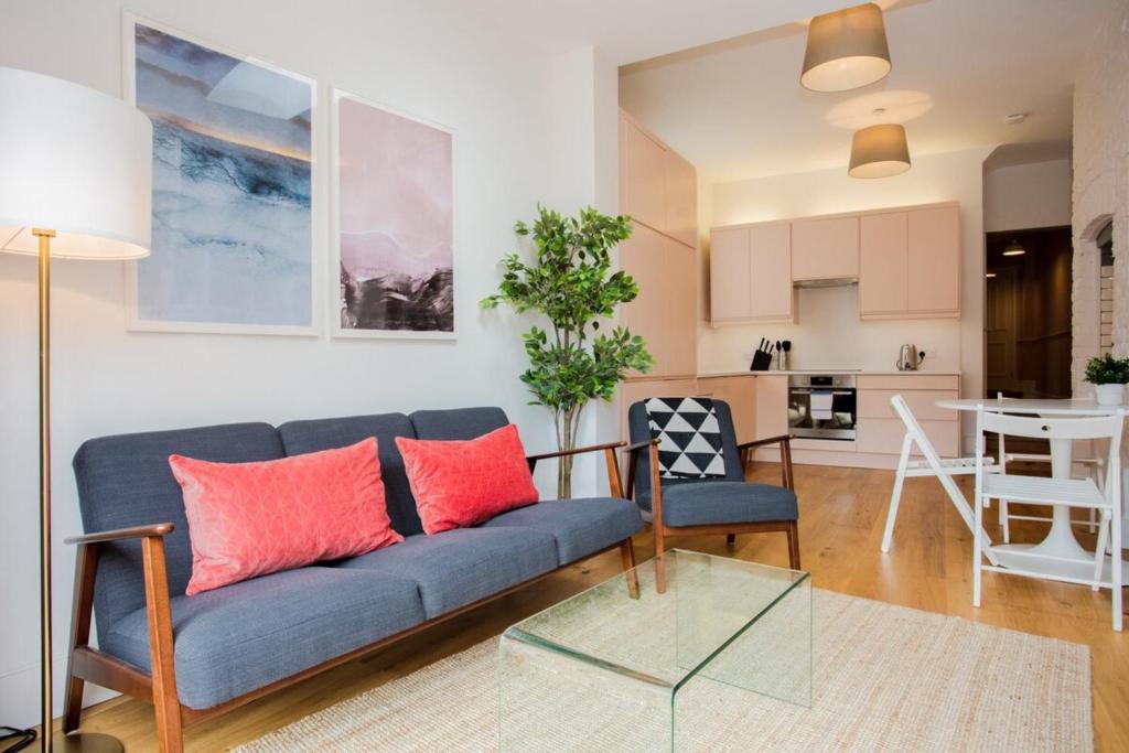 a living room with a blue couch and a glass table at Stylish & Modern 3 Bed Flat in NW London with Garden in London