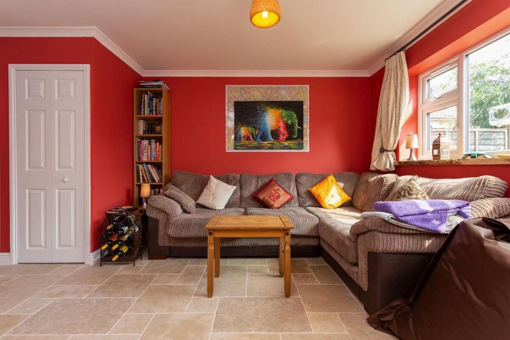 ロンドンにあるSpacious 3 Bedroom House with Garden in Bermondseyの赤い壁のリビングルーム(ソファ付)