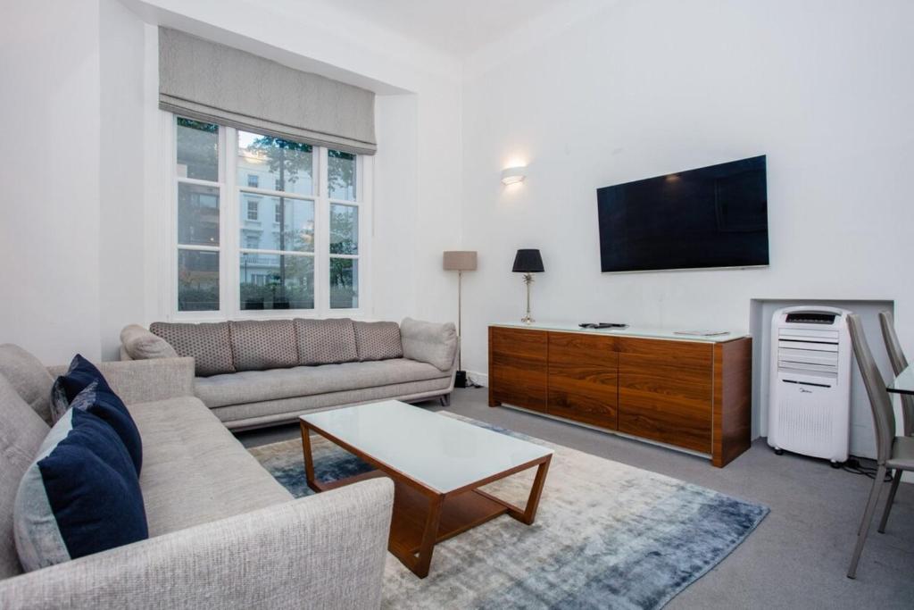 ロンドンにあるCosy 1 Bedroom Apartment Near Harrods Knightsbridgeのリビングルーム(ソファ、薄型テレビ付)