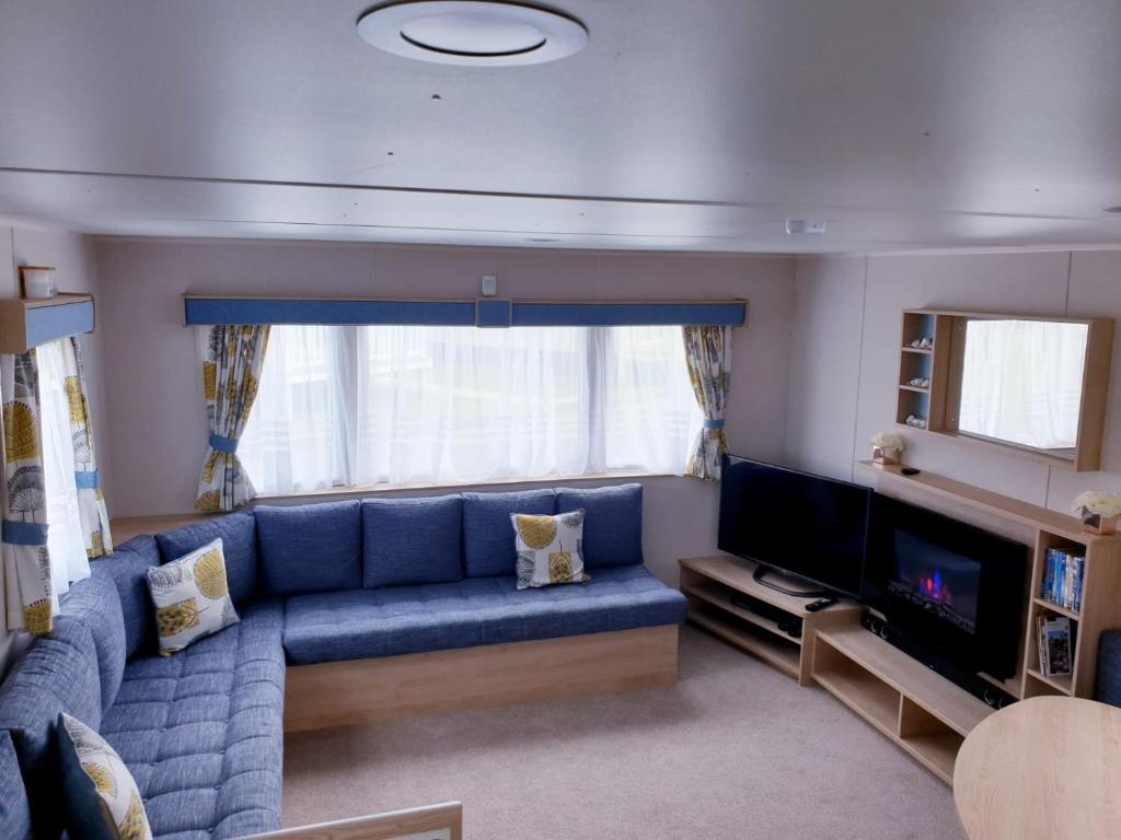 a living room with a blue couch and a television at The Abi Joseph @Combe Haven in Hastings