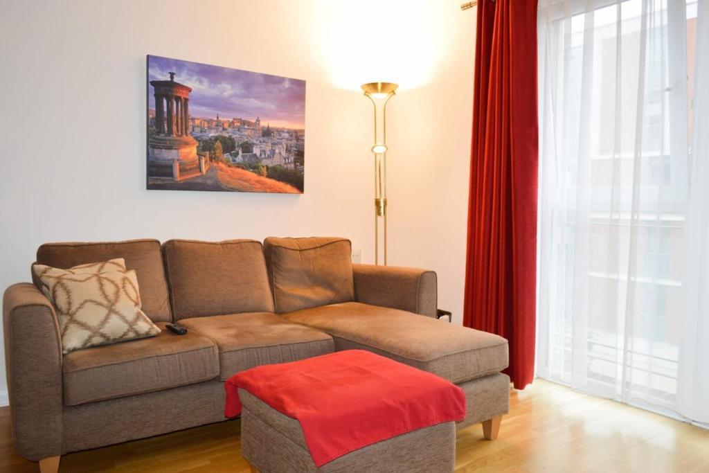 エディンバラにあるModern 2 Bedroom Property in Central Edinburghのリビングルーム(ソファ、赤いオットマン付)