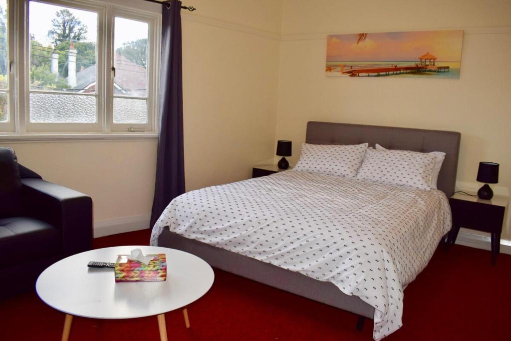a bedroom with a bed and a table and a window at Comfortable 3 Bedroom Apartment In Trendy Haberfield in Sydney