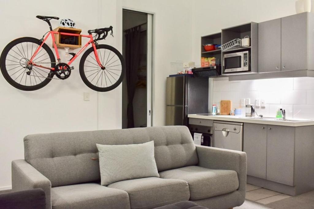 a bike hanging on a wall above a couch at Cozy Queen Street 1 Bedroom flat in the Heart of Central Business District in Auckland