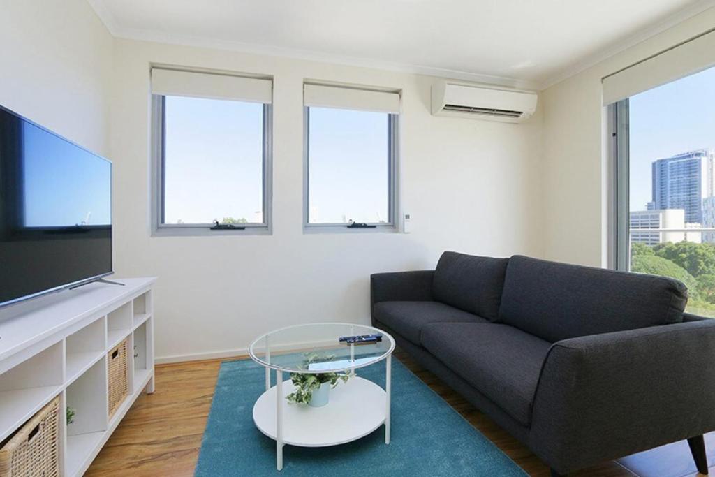 a living room with a couch and a tv at Stunning Two-Storey Apartment in Perth's CBD in Perth