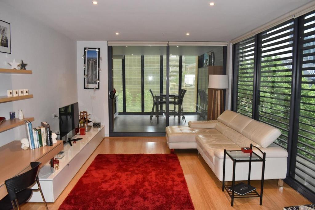 a living room with a couch and a red rug at Spacious 1 Bedroom Apartment in the Heart of Melbourne's CBD in Melbourne