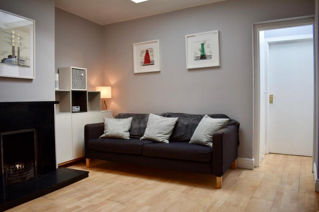 sala de estar con sofá negro y chimenea en Charming 2 Bedroom Cottage in Central Location en Dublín