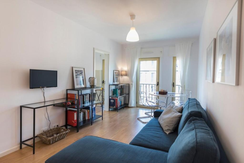 ein Wohnzimmer mit einem blauen Sofa und einem TV in der Unterkunft Comfortable Apartment in Campo Pequeno in Lissabon