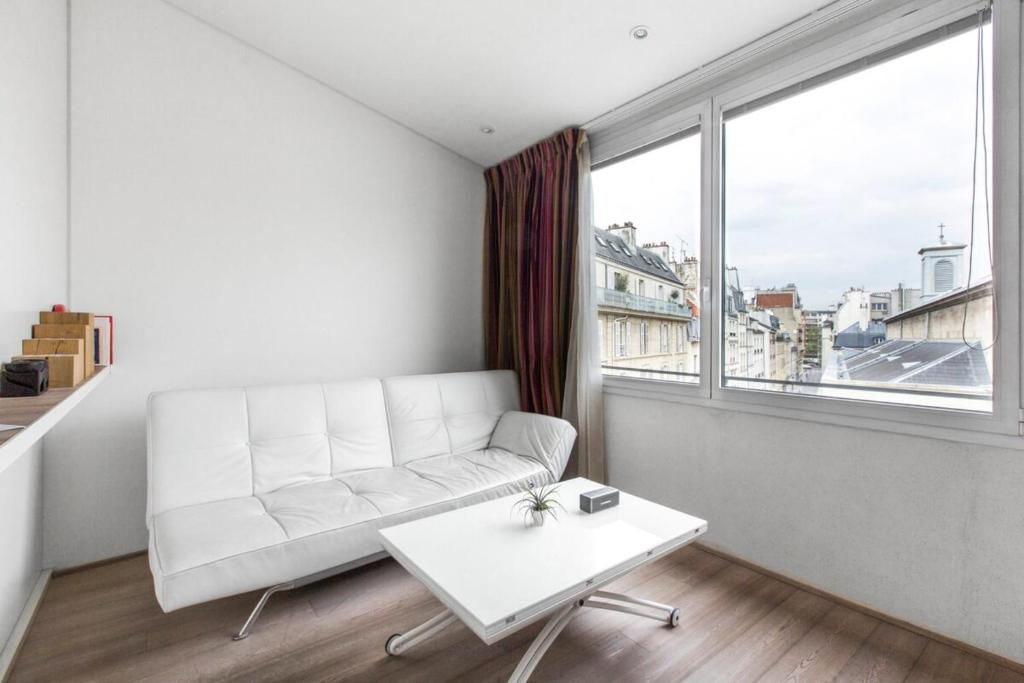 - un salon blanc avec un canapé blanc et une grande fenêtre dans l'établissement Modern Apartment in the Heart of the Marais, à Paris