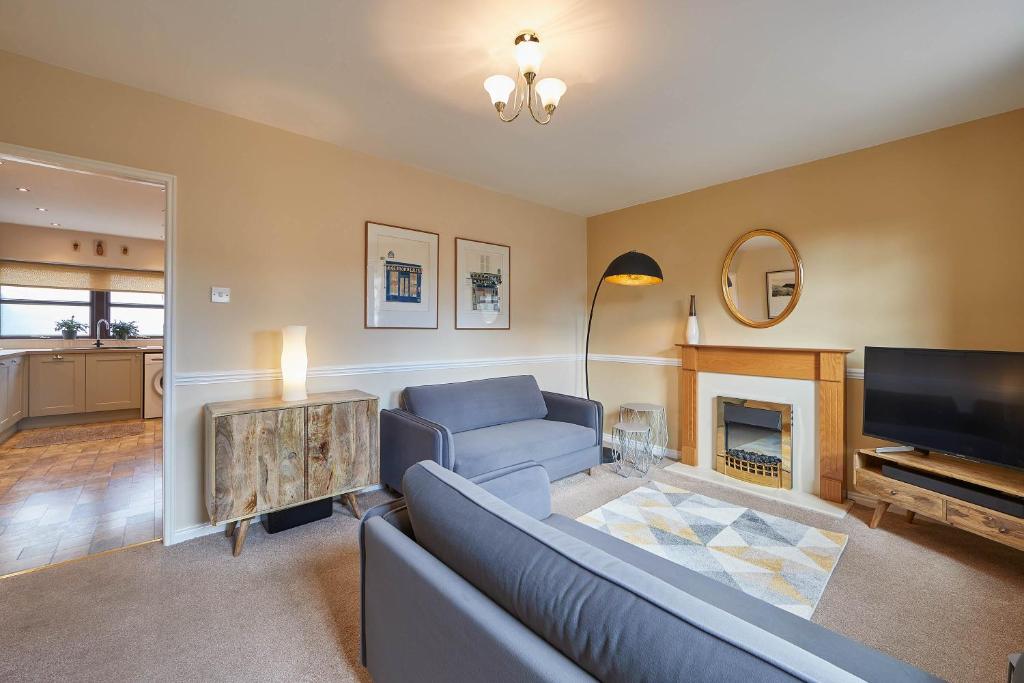 een woonkamer met een blauwe bank en een televisie bij Host & Stay - Wood Street Cottage in Barnard Castle