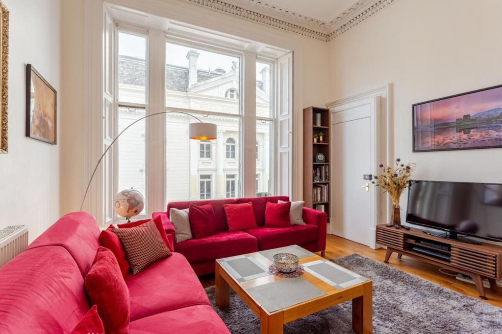 a living room with a red couch and a tv at Cozy 2 Bedroom Apartment at Heart of the Edinburgh in Edinburgh