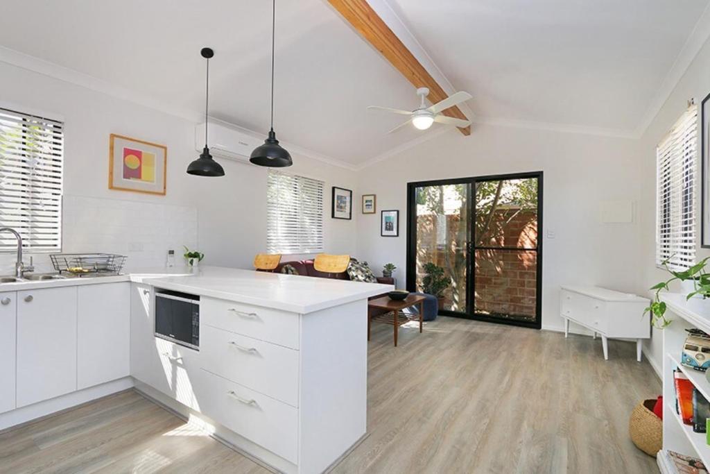 uma cozinha com armários brancos e uma sala de jantar em Comfortable Flat in Heart of Fremantle em Perth
