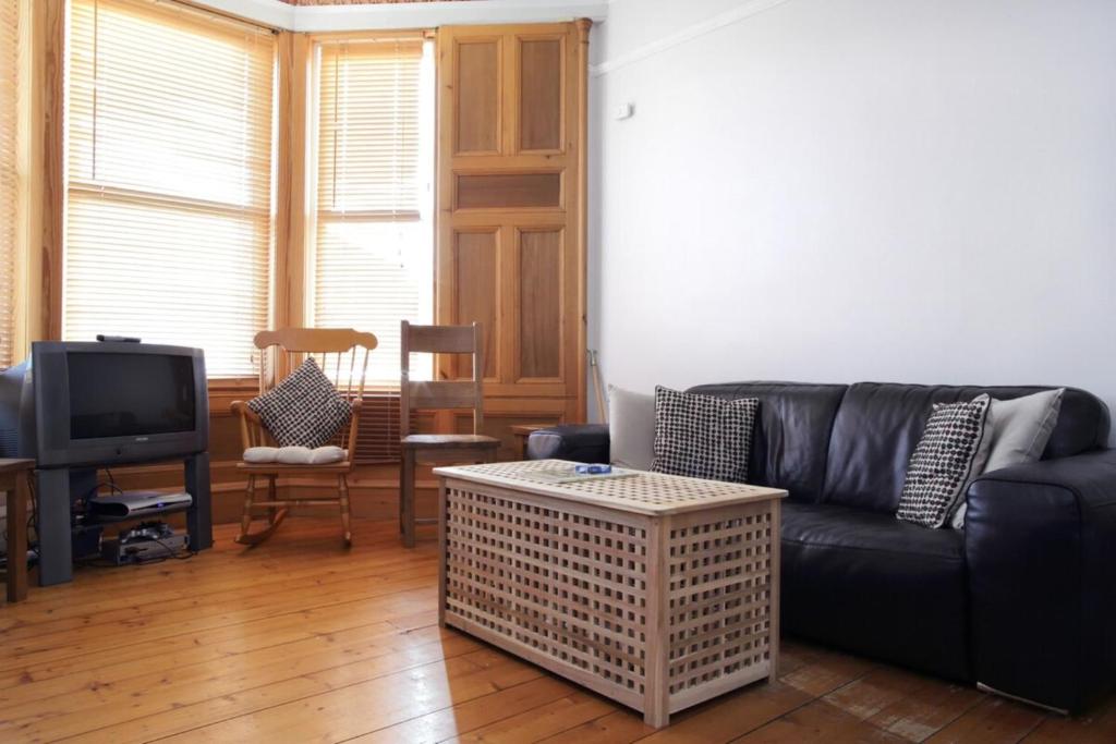 a living room with a black couch and a tv at Central and Spacious 2 Bedroom Flat With Garden in Edinburgh