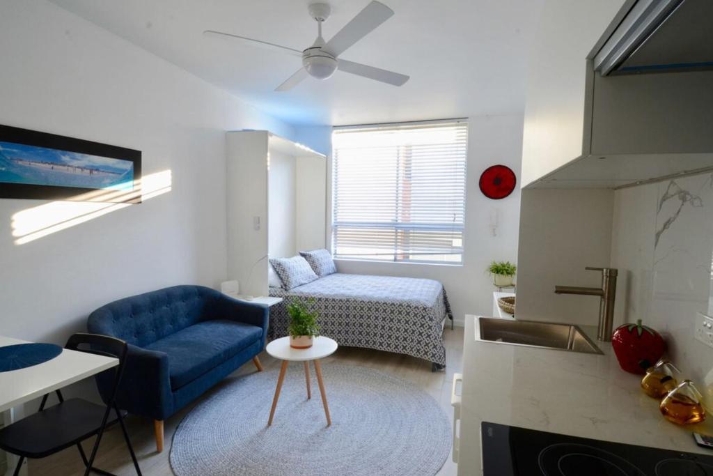 a living room with a blue chair and a couch at Cute Studio Apartment in Maroubra in Sydney