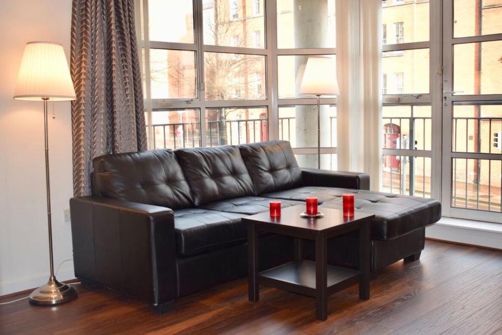 ein schwarzes Ledersofa im Wohnzimmer mit einem Tisch in der Unterkunft 2 Bedroom Apartment near historical Christchurch in Dublin