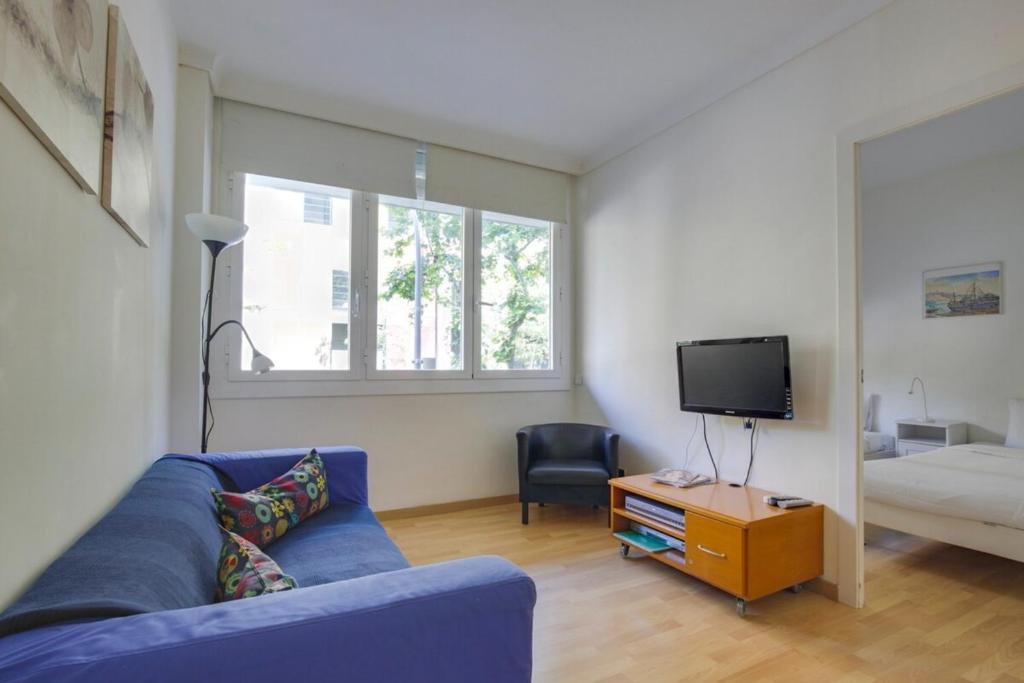 a living room with a blue couch and a tv at Cozy 2 Bedroom next to Arc de Triomf in Barcelona