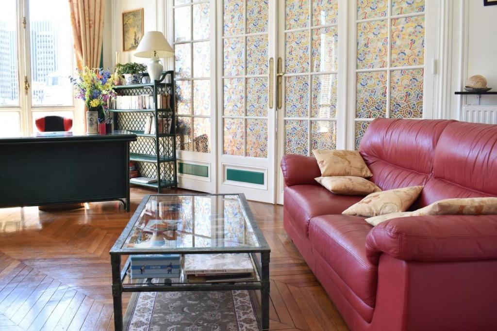 un salon avec un canapé rouge et une table en verre dans l'établissement Charming 2 Bedroom Apartment with view of Paris Gare de Lyon, à Paris