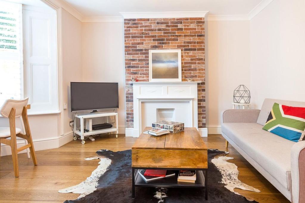 a living room with a couch and a fireplace at Beautifully Styled Modern Apartment With Garden in London