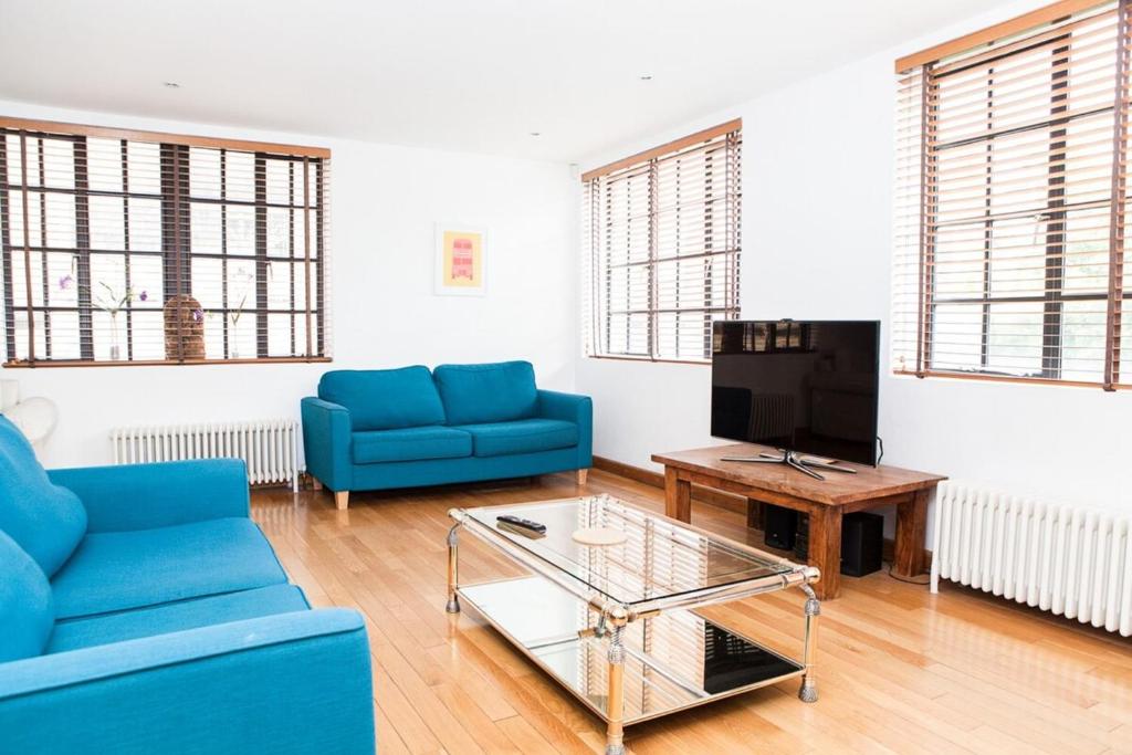 a living room with blue couches and a coffee table at Spectacular Central 4-Bedroom Close To London Eye in London